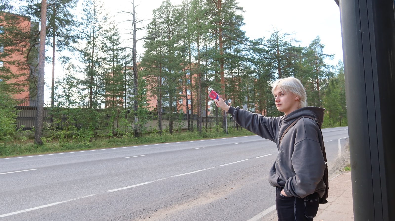 Young man waving his OSL travel card at an arriving bus.