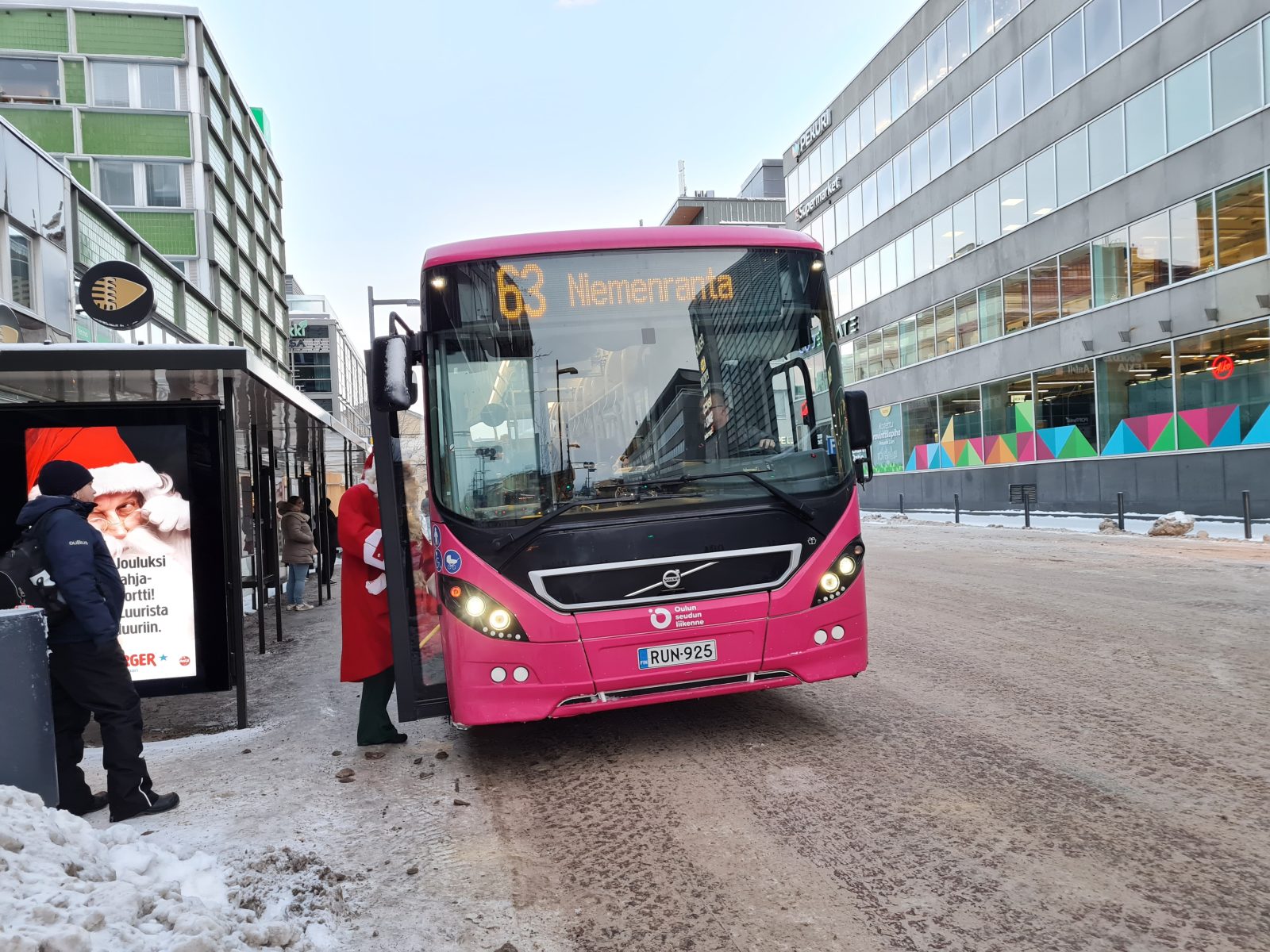 Oulun seuudn liikenten bussi 63 pysäkillä ja joulupukki nousemassa autoon.