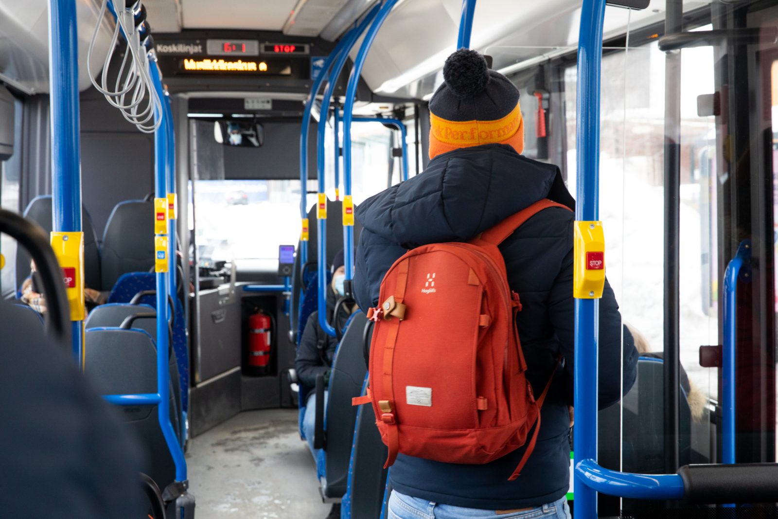 Matkustaja punainen reppu selässä talvella bussissa.