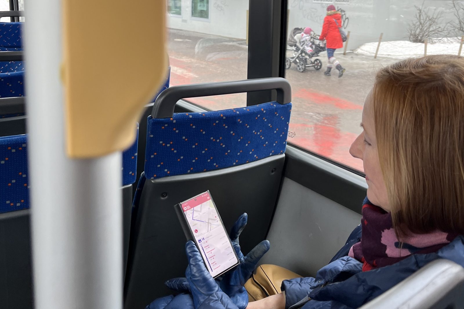 Woman sitting in a bus and watching her mobile ticket.