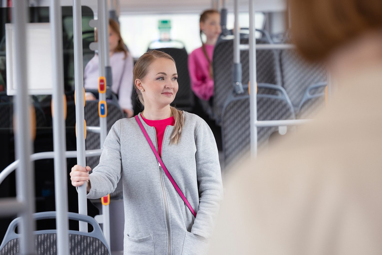 Woman holding to a bar inside the bus.