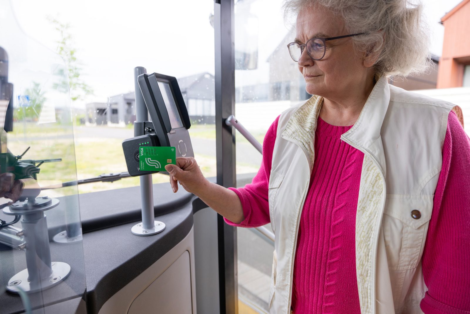 Grandma pays with a debit card at the bus ticket machine.